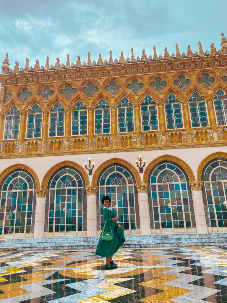 Black woman in long green dress smiles in front of the Ca' d'Zan at Ringling Museum in Sarasota